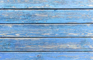 Textured surface of a old painted wood planks. Horizontal wooden boards with a peeling and cracked layer of blue paint. Aged natural wall material, rustic fence. Retro background with copy space.