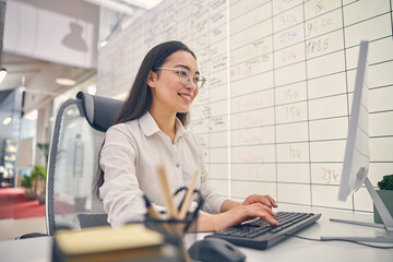 Positive delighted young woman working at her project