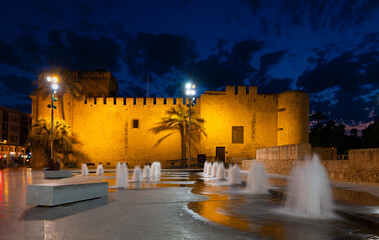 In the evening in the Spanish palm city of Elche. The castle is in the blue hour with water...
