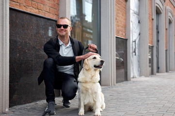 young sick man with helpful guide dog in city streets, sit having rest, man and golden retriever, in love - Powered by Adobe