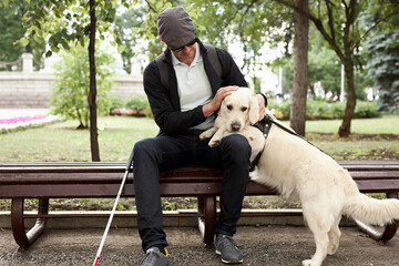 young blind man stroking guide dog in the street, caring favorite pet, best friend. outdoors