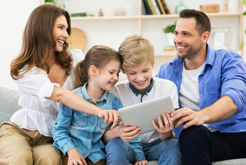 Parents And Children Using Tablet Watching Film Together At Home