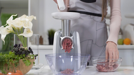 Making minced meat in an electric meat grinder from fresh beef at home. Pile of chopped meat. Electric mincer machine with fresh chopped meat. Preparation of minced beef with an electric meat grinder.