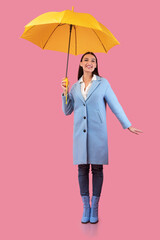 Portrait of young woman standing with yellow parasol