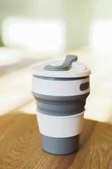 Gray foldable silicone cup for drinks without plastic in the style of zero waste on a interior background, close-up. Product photography. Store content