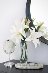 Table with cosmetic products and a mirror in a bright room. Bathroom. flowers