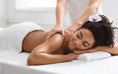 Obraz na płótnie Canvas Relaxed black girl enjoying full body massage at new spa