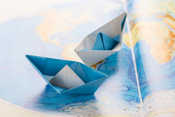 Paper boats on world map. Concept of traveling or military exercise.
