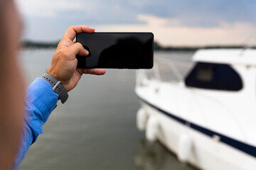 Man photographing Yacht with smartphone at the river