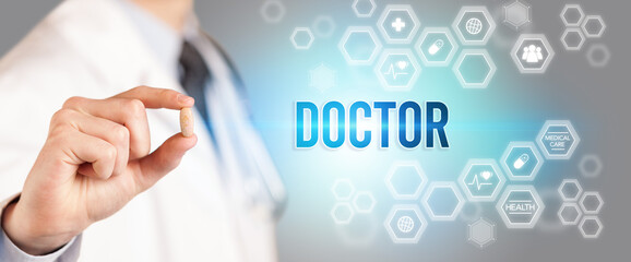 Close-up of a doctor giving you a pill with DOCTOR inscription, medical concept