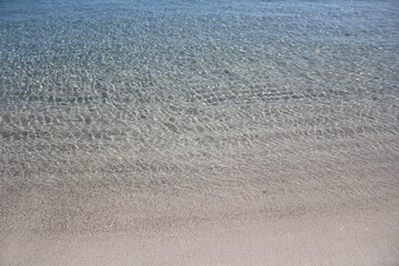 clear shimmering water at a sunny turquoise colored beach 