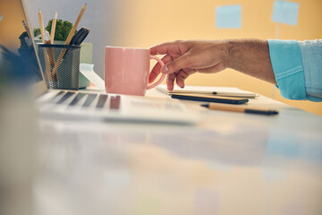 Busy office worker stretching hand to pink cup