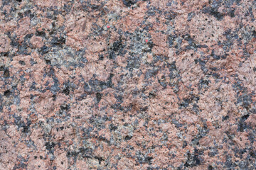 Granite texture. Natural pink granite with a grainy pattern. Stone background. Solid rough surface of rock. Durable construction and decoration material. Close-up.