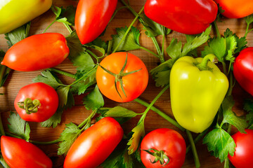 Tomatoes and bell peppers on a wooden table background.