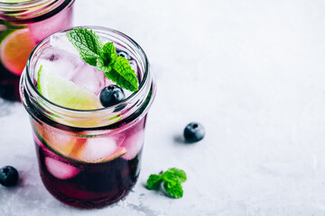 Blueberry Mojito with lime and fresh mint. Iced cold summer drink in glass jar.