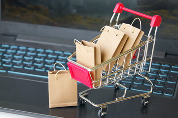 Mini shopping cart with small craft bags on the background of the keyboard.