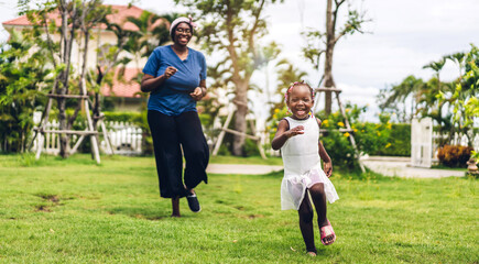 Obraz premium Portrait of enjoy happy love black family african american mother and little african girl child smiling running and having fun moments good time in summer park at home