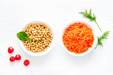 Vegetarian meal. Chickpeas and carrot in bowls on white table top view
