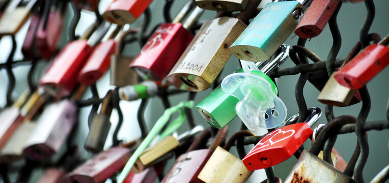 colourful Love padlocks and а
pacifier between them  on the Hohenzollern Bridge in Cologne, Germani. Selective focus