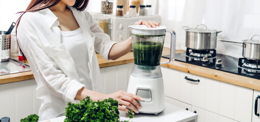 Healthy woman enjoy making green vegetables detox cleanse and green fruit smoothie with blender in kitchen at home.dieting concept.healthy lifestyle