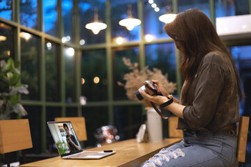 Woman is learning to use camera thru tutorial by laptop. Asian female watching online e-teaching training workshops for camera function by notebook in the living room