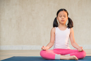 calmness and relax, female freedom happiness. home practice room background. little asian girl meditates while practicing yoga. child happiness. toned picture healthy life. yoga concept.