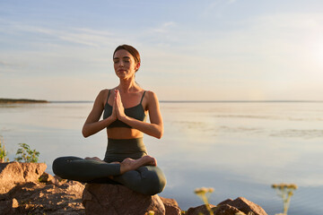 Beautiful young woman meditating on the beach