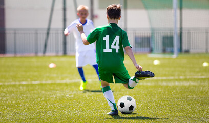 Boys kicking football on a grass field. School age soccer boys playing game. School soccer stadium...