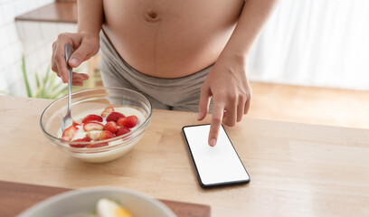 Obraz na płótnie Canvas Pregnant woman using mobile phone while having healthy food.