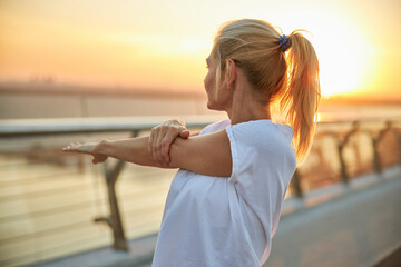 Female in a t-shirt doing a shoulder stretch