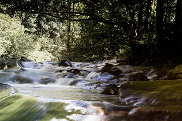 Krajobraz kaskady wodne z dużymi głazami i roślinnością na brzegach © Monika