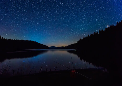 Long time exposure night landscape with starry sky above a mountain lake, Beglik dam in Rhodopi Mountains, Bulgaria