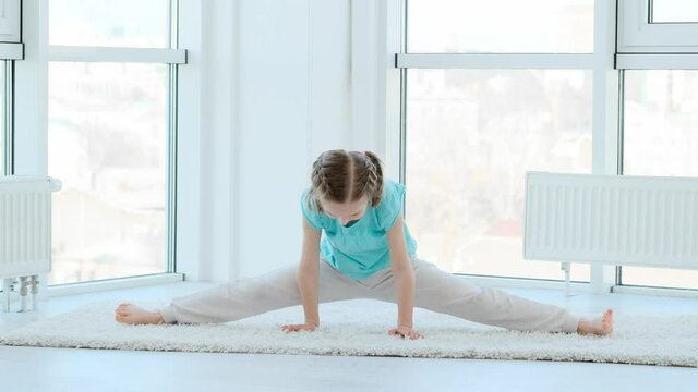 Cute little girl performing gymnastics in bright room