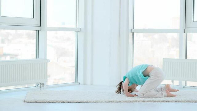 Active little girl doing crotch in light room