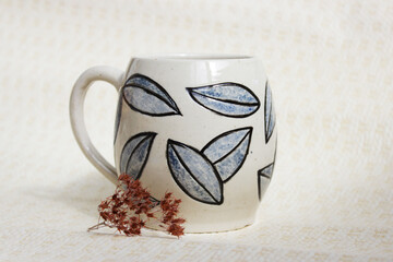 handmade ceramic cup with leaves. clay covered with engob, glaze and passed two firing.