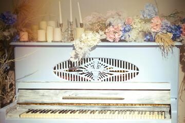 Vintage blue piano, close-up. Retro musical instrument with red flowers and candles