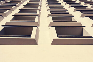 Identical convex windows of a concrete building sloping upwards