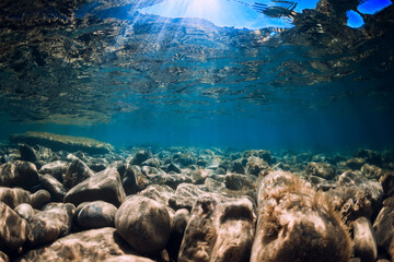 Underwater view with stones and blue transparent water.