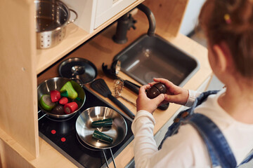 Little girl in casual clothes have fun by playing with toys on the kitchen