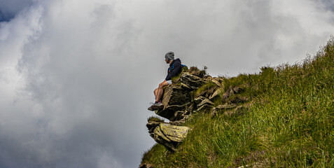 Man sitting on a rock in the mountains. Cloudy weather in the mountains. Bieszczady Poland.