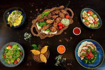 Barbecue on the grill. Mashed potatoes with pickles. Salad with quail eggs, pine nuts and tomatoes. Duck in bacon with broccoli, shrimp, salmon, caviar egg