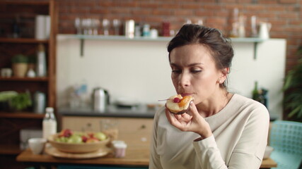 Woman looking at camera with fancy cake in hand. Girl biting dessert at home.