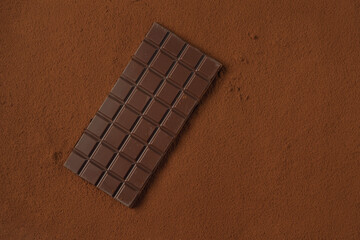 Chocolate bar on cocoa powder background.