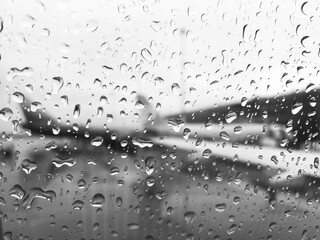 The blurred wing of the plane is visible through a drop of rain on the window of the aircraft