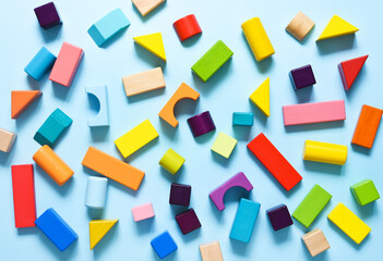 Wooden colorful cubes on a light blue background. View from above. Construction.