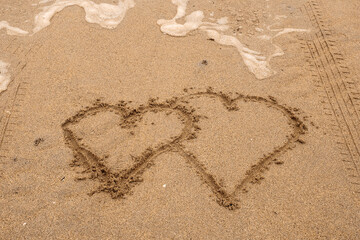 Sign on a sand. Two hearts close together. Concept love and relationship