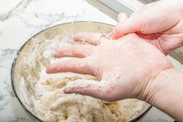Thick dough is manually mixed in a transparent bowl.