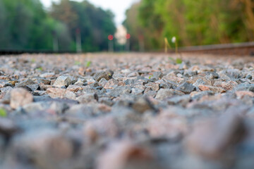Blurred background with gravel, railroad tracks and closed semaphores with prohibitive red lights.