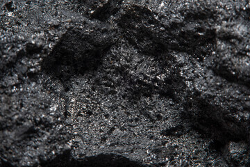 Blurred black background in soft focus with hard coal at high magnification. An image on the theme of geology and the extraction of minerals and natural fuels.