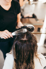 Naklejka premium Beautiful brunette woman with long hair at the beauty salon getting a hair blowing. Hair salon styling concept.